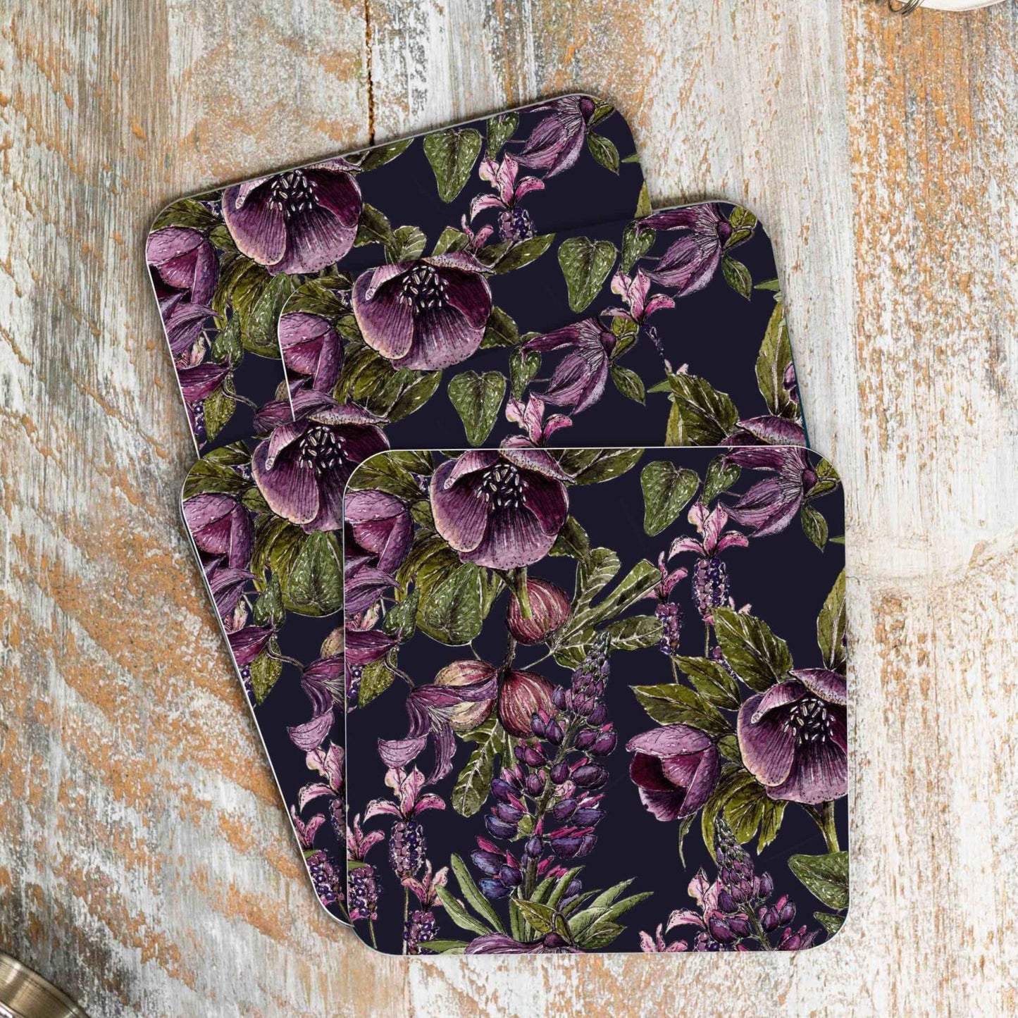 Stack of 4 coasters with purple and black floral design. Photographed on a wooden surface.