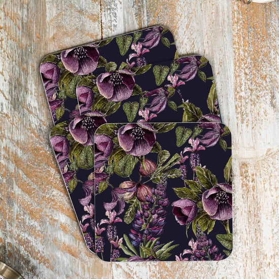 Load image into Gallery viewer, Stack of 4 coasters with purple and black floral design. Photographed on a wooden surface.
