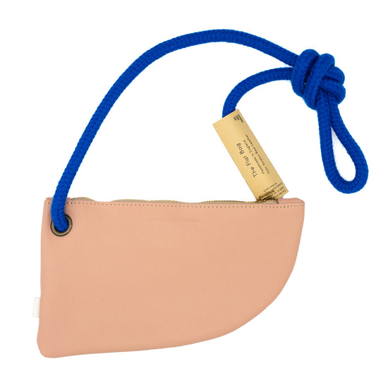 A pink leather crossbody bag with a blue rope strap. The bag has a curved shape and a zipper closure. A tag is attached to the strap reads with product info.