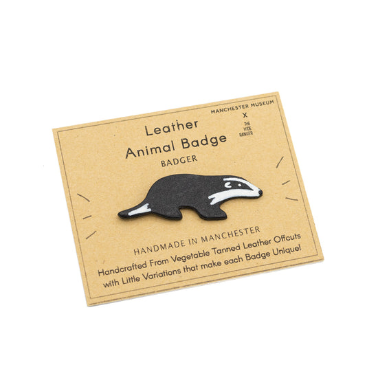 Handmade and hand painted badge in the shape of a badger, against a brown backing card with The Hide Ranger's logo and product information.