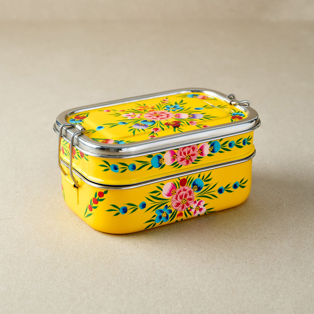 Yellow floral-patterned tiffin lunch box on a beige background