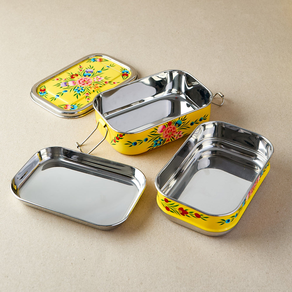 Opened tiffin lunch box showing the two rectangular containers and 2 lids with floral designs on a beige background.