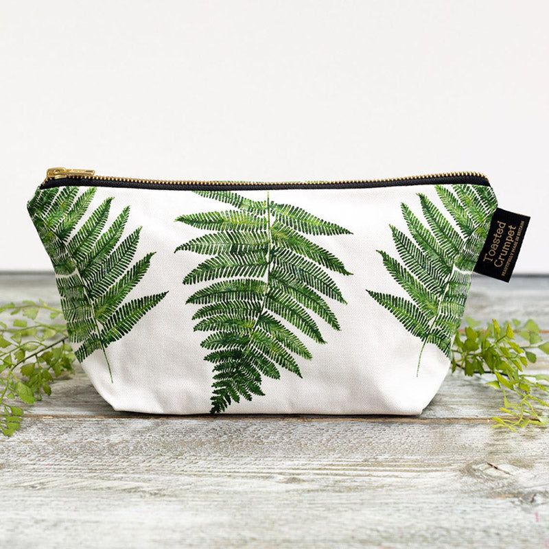 Zip bag with white background and fern pattern photographed on a grey wooden surface