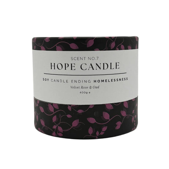 A black and purple cylindrical candle container with text about the product, featuring a design of purple leaves on a black background.