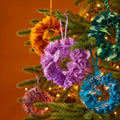 Handcrafted mini wreath made from recycled sari fabric in assorted colours and textures, finished with a hanging loop for festive decoration.