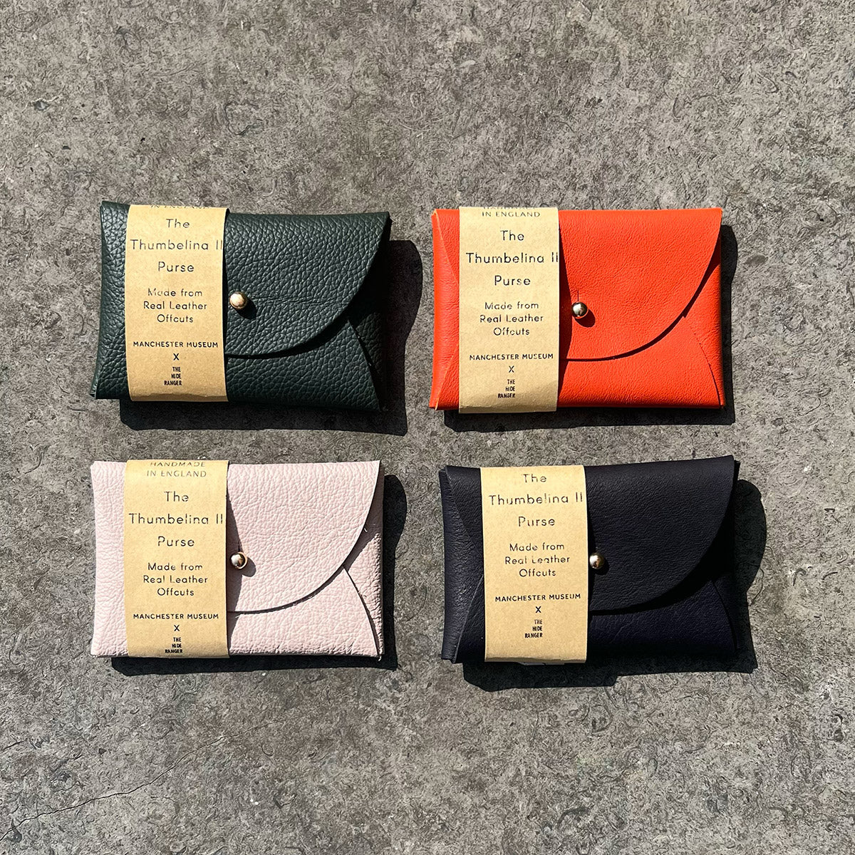 4 rectangular leather purses placed in a grid of four. In colours sage green, orange, pale pink and navy.