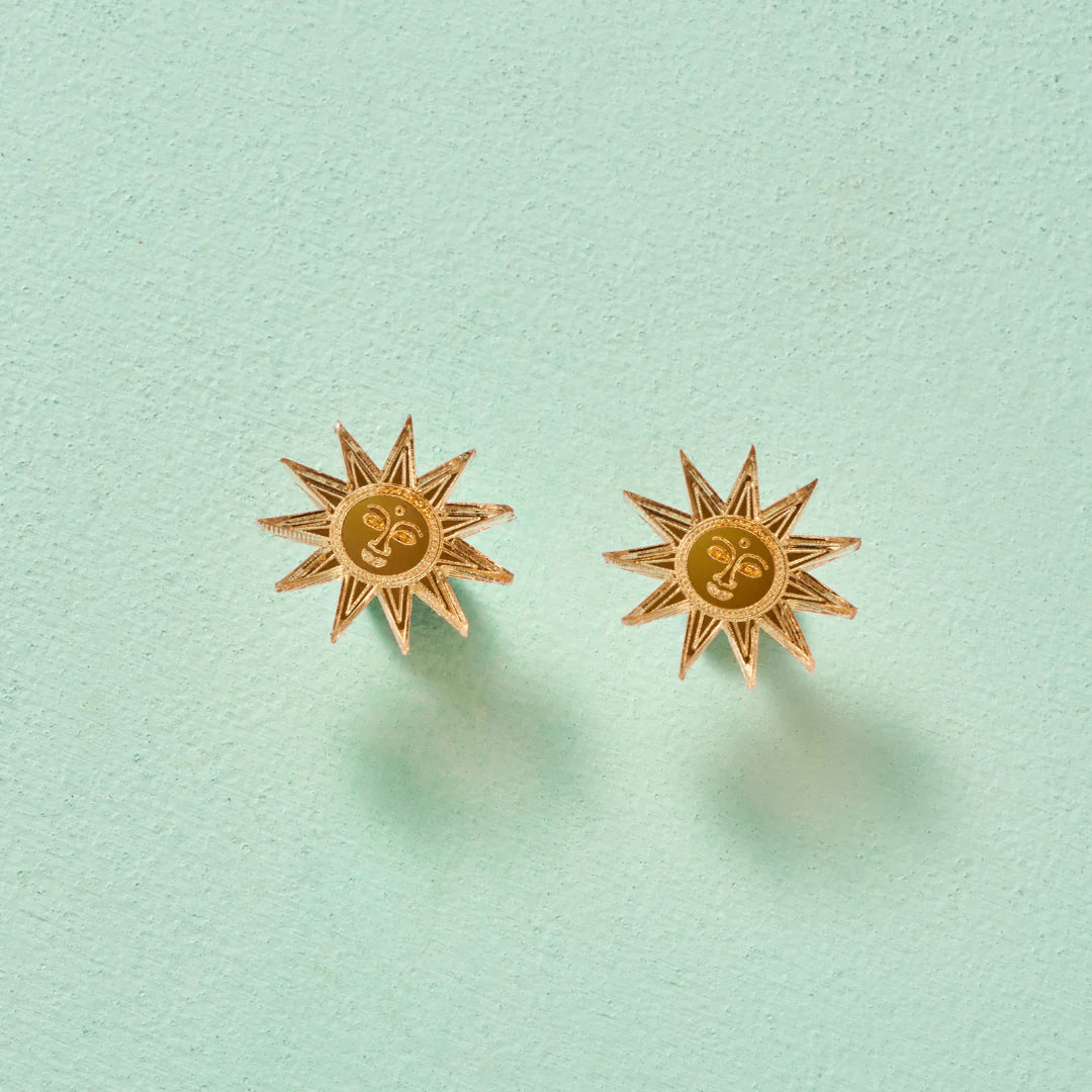 Load image into Gallery viewer, A pair of sun studs with engraved faces in the round centre. Pale sage green backdrop.
