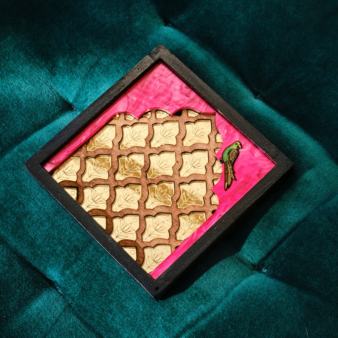 Load image into Gallery viewer, A black square tray shown at an angle on a dark teal fabric backdrop. A green parrot in the righthand corner against a hot pink background. The centre has a jali-inspired lattice pattern with wood and gold.
