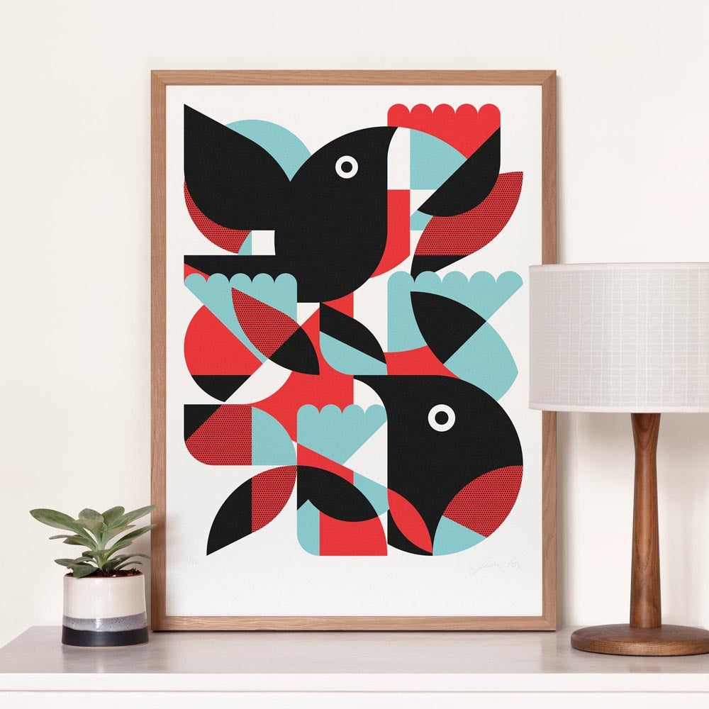 Framed abstract art print with geometric bird shapes on a white wall.