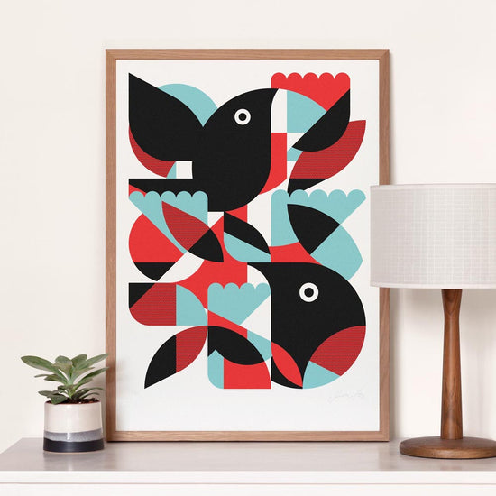 Framed abstract art print with geometric bird shapes on a white wall.
