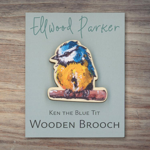 Wooden brooch with a blue tit motif. The brooch is on a grey backing card with Ellwood Parker branding.