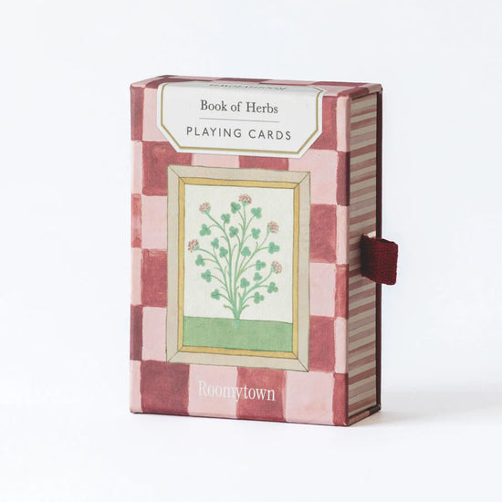 Playing cards box in light and dark pink squares with a floral illustration on the front.
