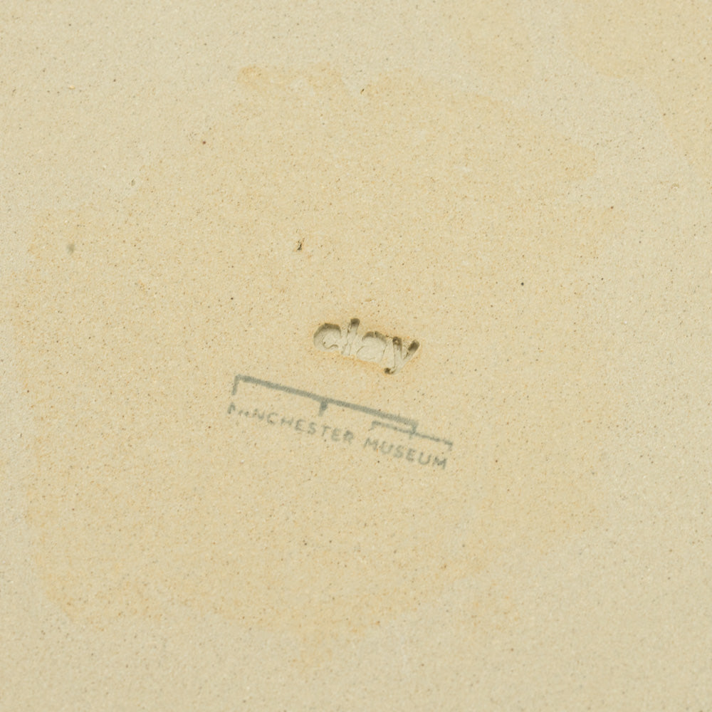 Load image into Gallery viewer, Detail of the back of a plate with the word Clay engraved and Manchester Museum logo stamped beneath

