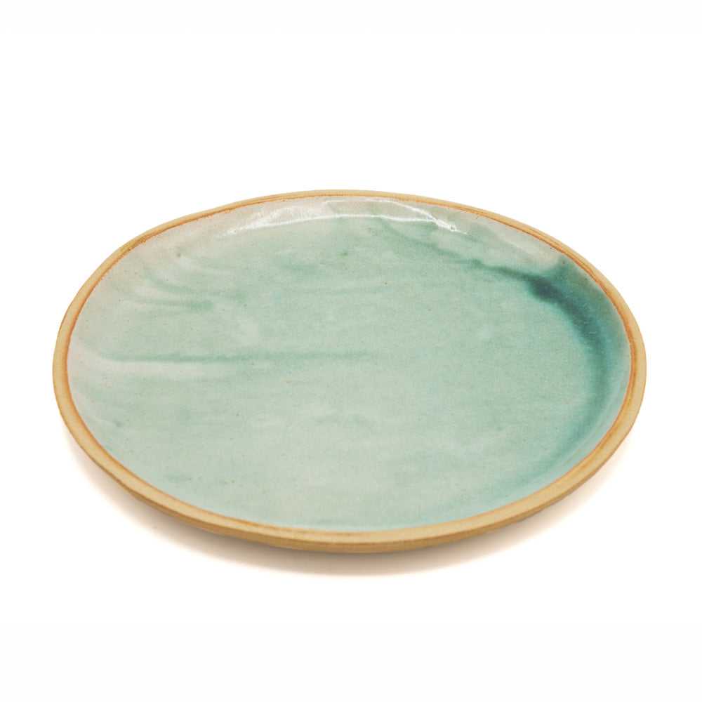 Handmade plate made with a turquoise glaze - with unglazed rim. Photographed against white background.