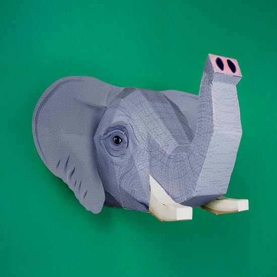Load image into Gallery viewer, The assembled elephant head in a three-quarter angle against a green background. The trunk is raised.
