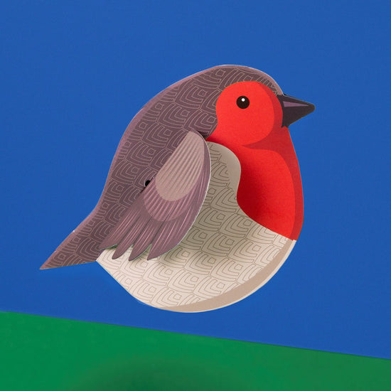 Load image into Gallery viewer, The assembled robin in a side view against a blue and green background.
