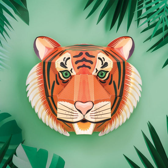 Front view of the assembled tiger head on a pale green background with darker green leaves poking in from around each corner.