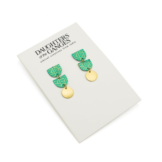 Earrings made up of 3 hanging shapes. Top two are green semi-circles with gold art deco pattern. The bottom shape is a gold circle. Presented on a white Daughters of the Ganges branded backing card. White background.