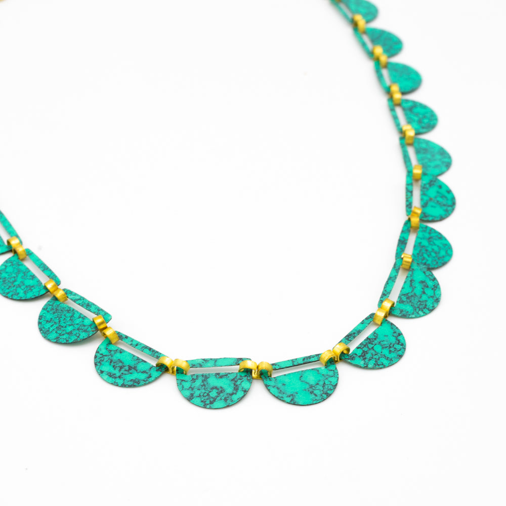 Load image into Gallery viewer, Close up of a necklace comprising of a number of green semi-circles bound together with gold fastenings. Photographed against a white background.
