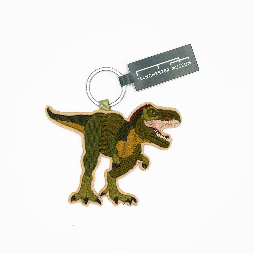 Dinosaur keychain with Manchester Museum tag on a white background