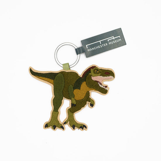 Dinosaur keychain with Manchester Museum tag on a white background