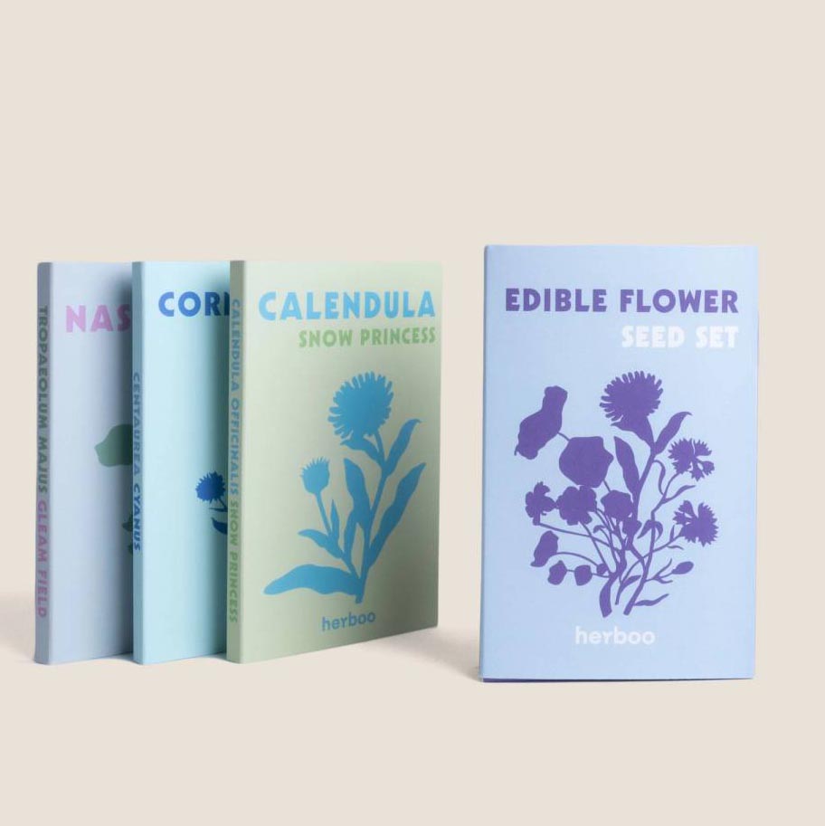 Four pastel-coloured boxes of flower seeds, with one of them being a set of edible flower seeds facing foward.