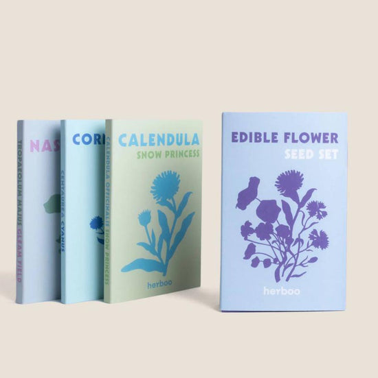Four pastel-coloured boxes of flower seeds, with one of them being a set of edible flower seeds facing foward.