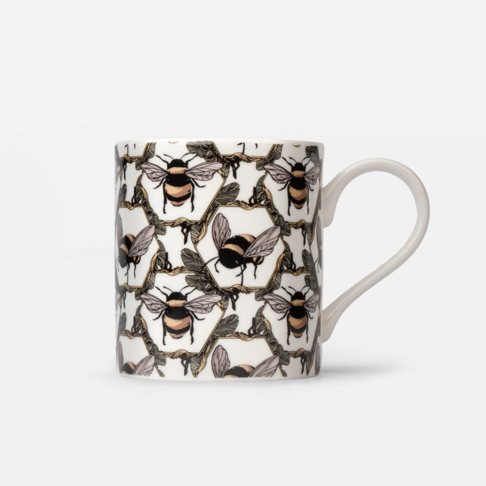 A white ceramic mug featuring an all-over pattern of detailed bumblebees in a honeycomb pattern, with a clean white handle, set against a light gray background.