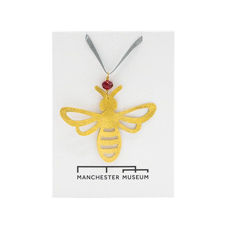 Load image into Gallery viewer, bee decoration made with hammered brass photographed on top of Manchester Museum branded backing card
