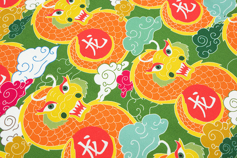 Close up of tea towel with a green, yellow, orange, and red dragon print