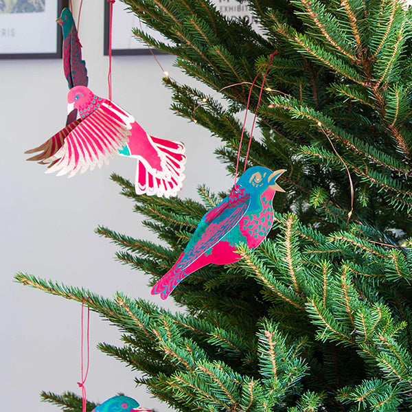 Various coloured birds made out of recycled paper hung on a Christmas tree.