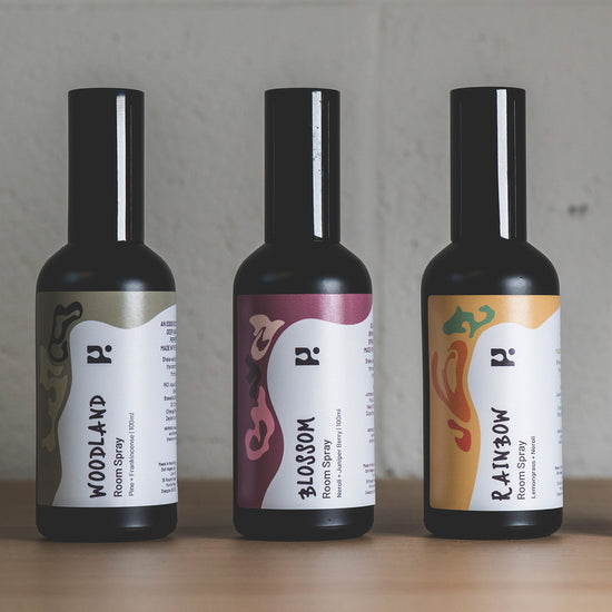 Three room spray bottles with colourful labels against a grey backdrop.