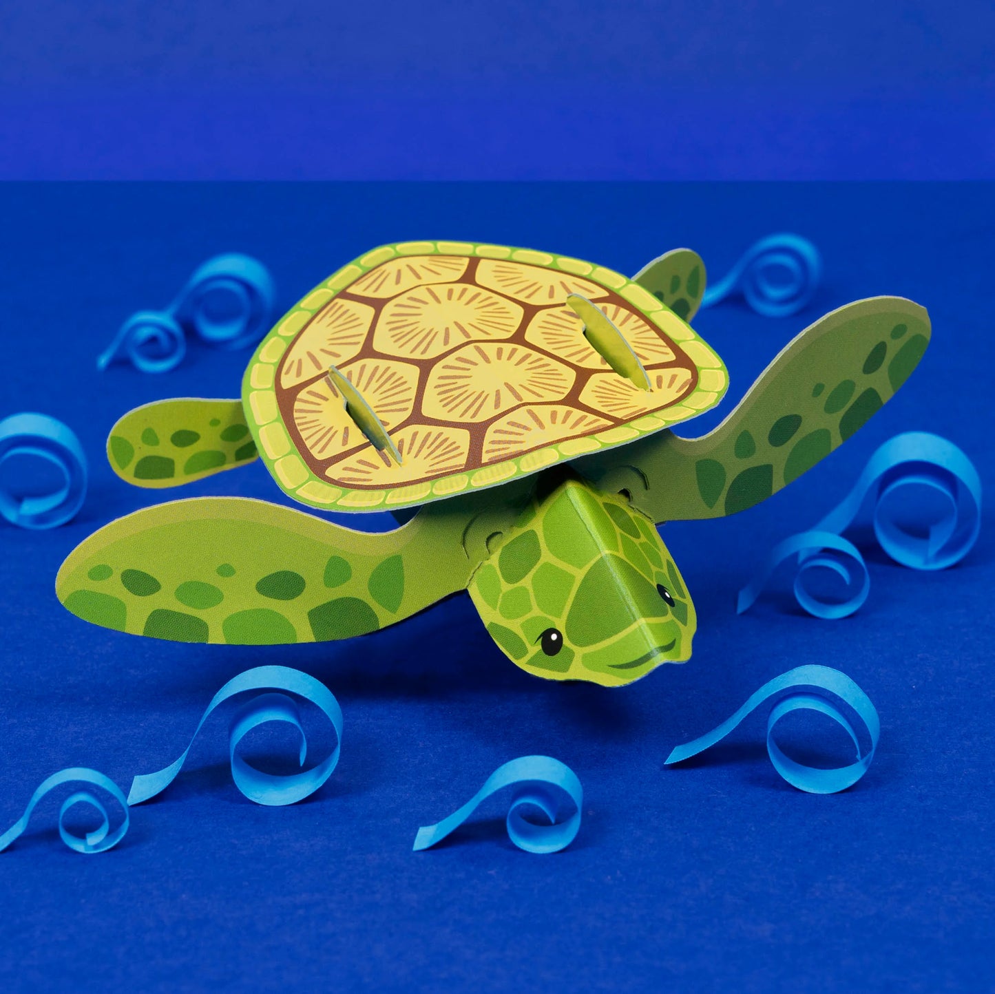 A small turtle made out of card, against a blue background