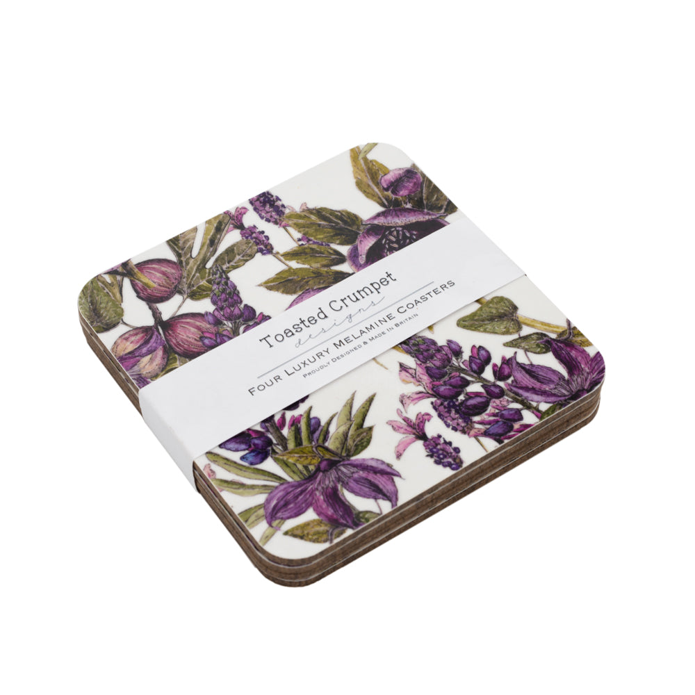 Stack of 4 coasters with purple and black floral design.  White belly band label with Toasted Crumpet branding on it. White background.