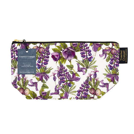Rectangular cosmetics bag with white, purple and green floral pattern design, photographed against white background. Bag has 2 Toasted Crumpet branded. labels attatched.