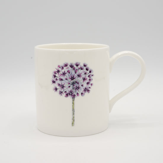 Mug with an illustration of an allium flower. Photographed against a white background.