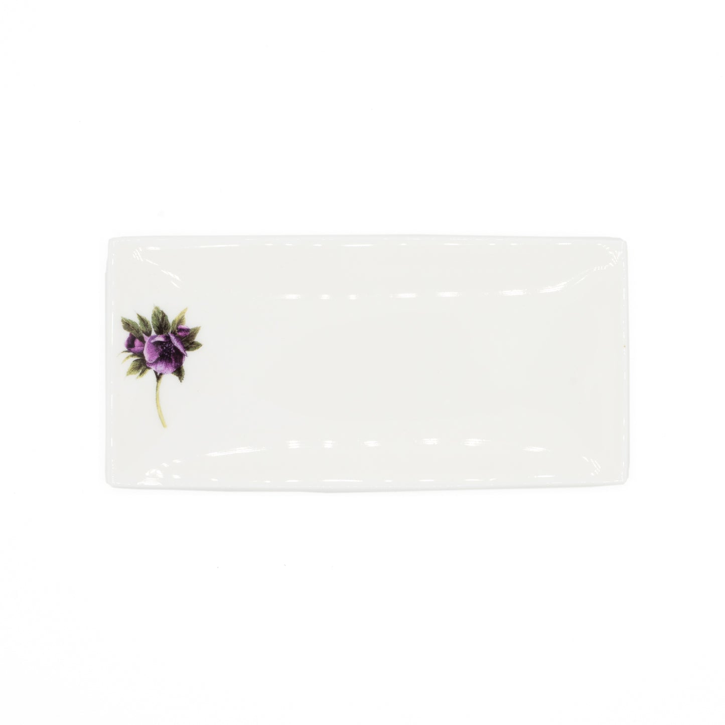 White rectangular soap dish with an illustration of a hellebore flower. Photgoraphed against white background.