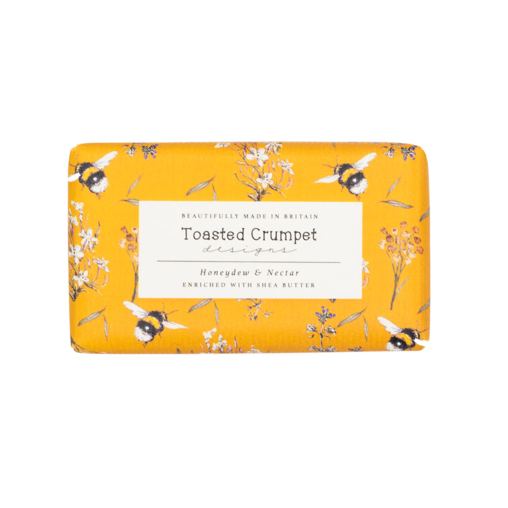Rectangular soap wrapped in orange packaging with pictures of bees. Photographed birds-eye view against white background