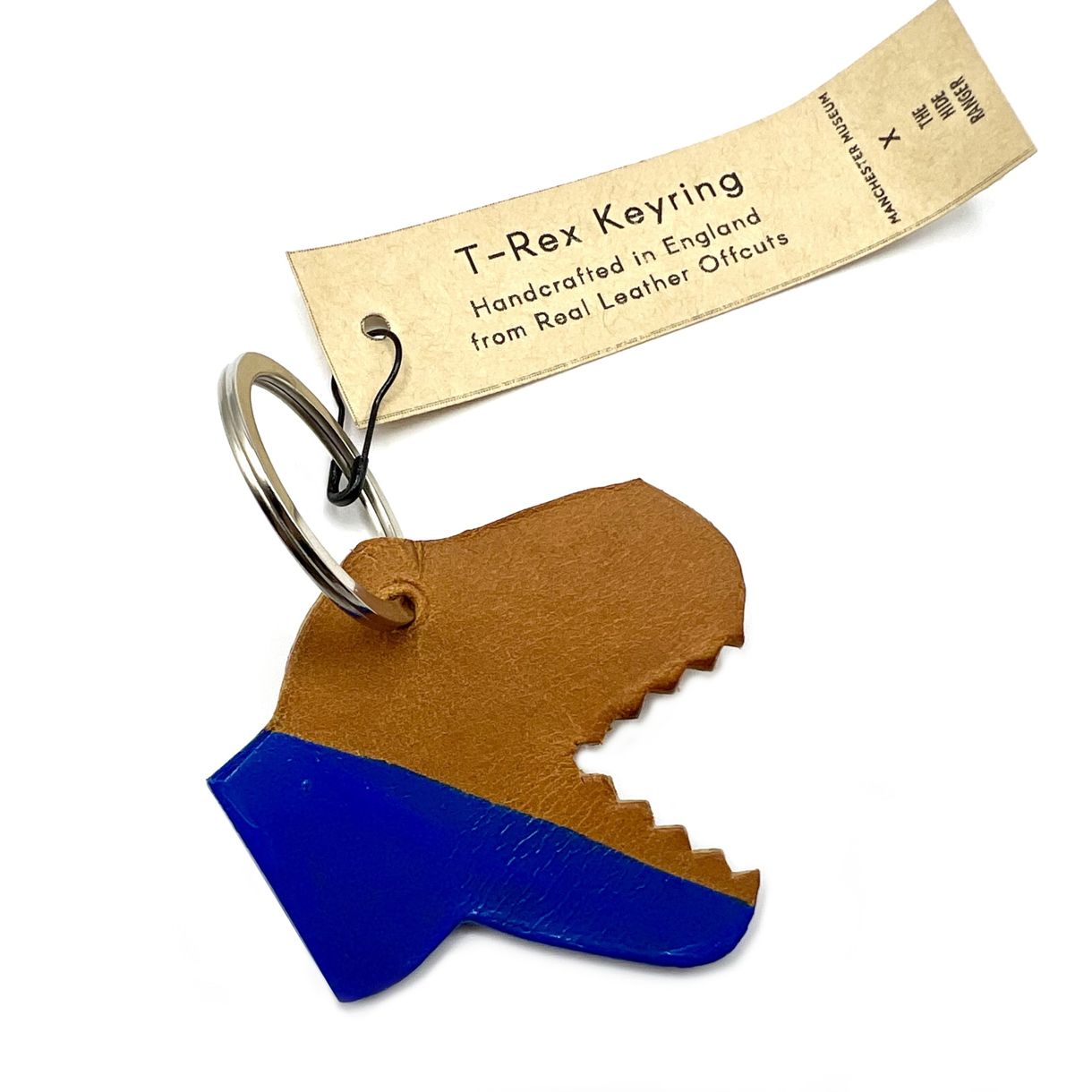 A T. rex head shaped keyring with open, toothed mouth. The bottom half of the head is painted blue. The keyring is where the eye would be and a paper swing tag is fastened to the keyring with a black safety pin. Tag text: T-Rex keyring. Handcrafted in England from real leather offcuts.