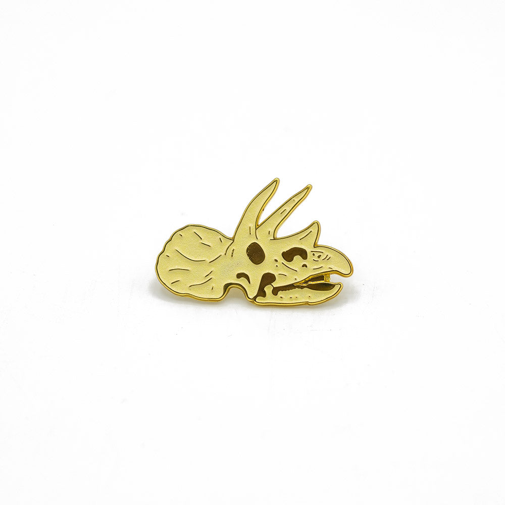Gold triceratops dinosaur pin on a white background