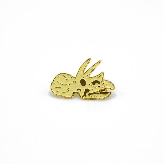Gold triceratops dinosaur pin on a white background