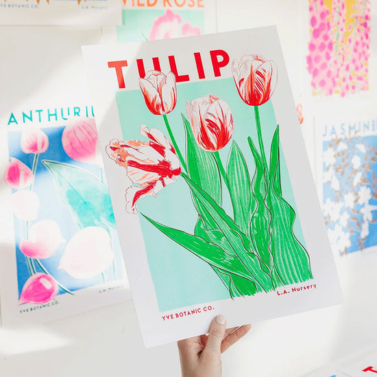 A person holding a green and red Risograph print of a tulip