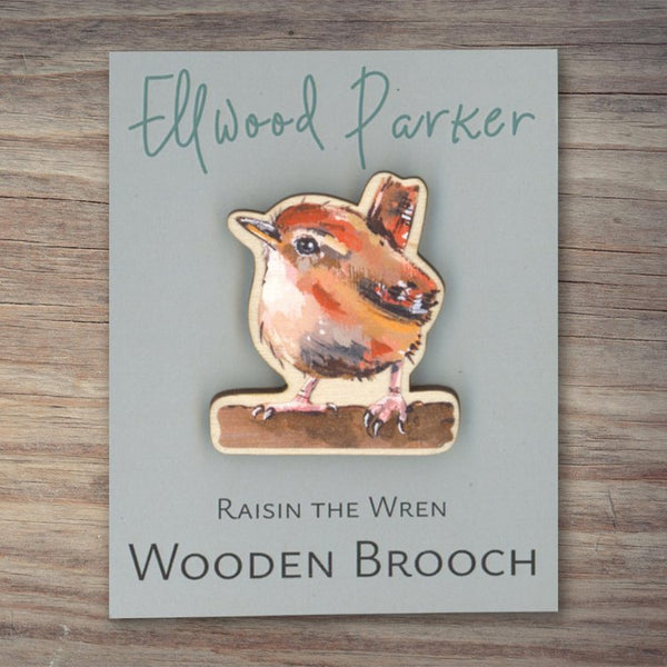 Wooden brooch with a wren motif. The brooch is on a grey backing card with Ellwood Parker branding.