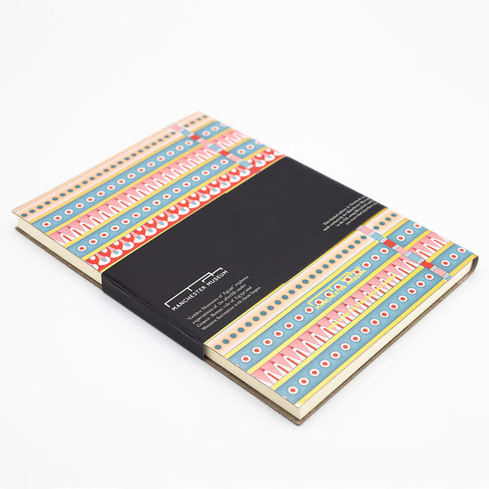 Rear angled view of the patterned notebook with the black belly band and Manchester Museum branding.