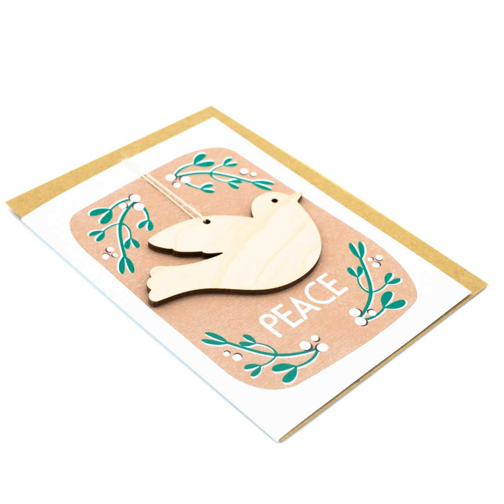 Load image into Gallery viewer, Card with brown envelope tucked inside, white background. Wooden dove decoration with the word &amp;#39;Peace&amp;#39; underneath. Mistletoe border.
