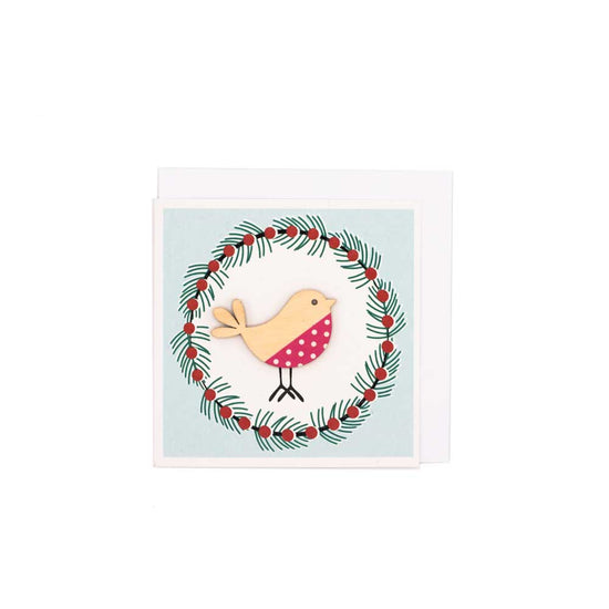 Square card with white envelope tucked inside, white background. Wooden robin decoration at the centre of a Christmas wreath.