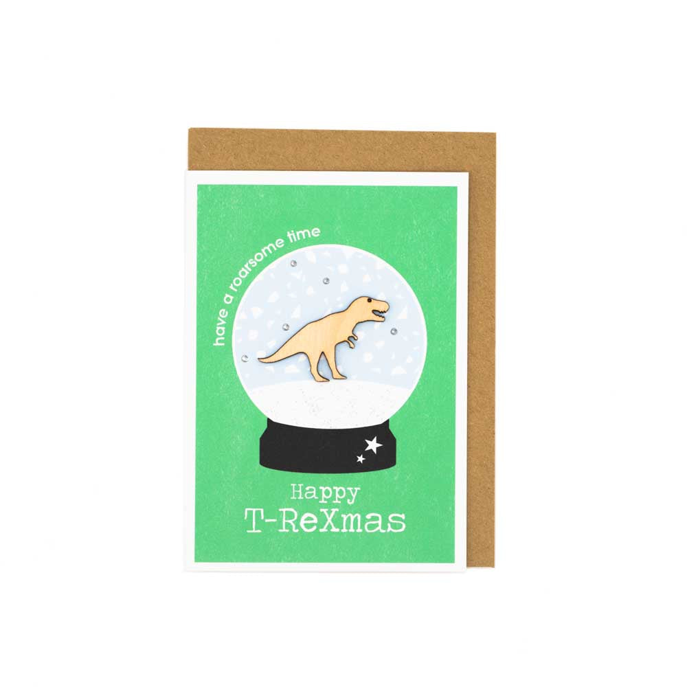 Card with brown envelope tucked inside, white background. Wooden T.Rex decoration at the centre of a snow globe.