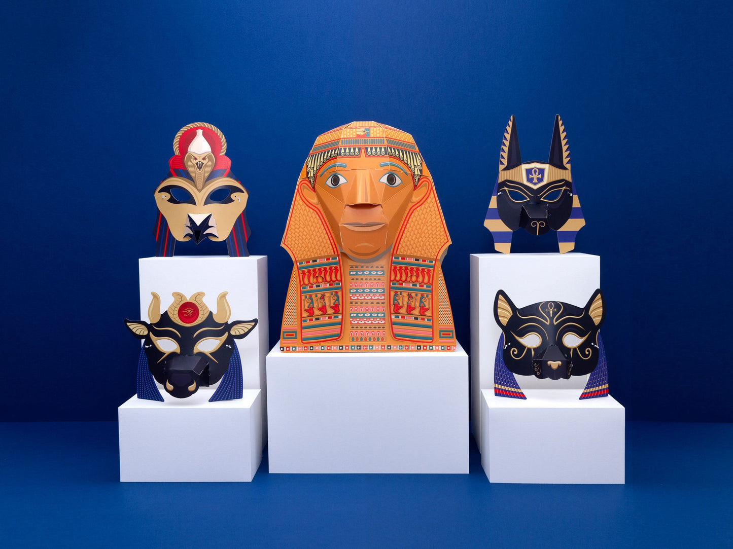 The headmask in a lifestyle shot with the four animal masks around it. All five masks are on vraiously sized white rectangular boxes and the background is blue.