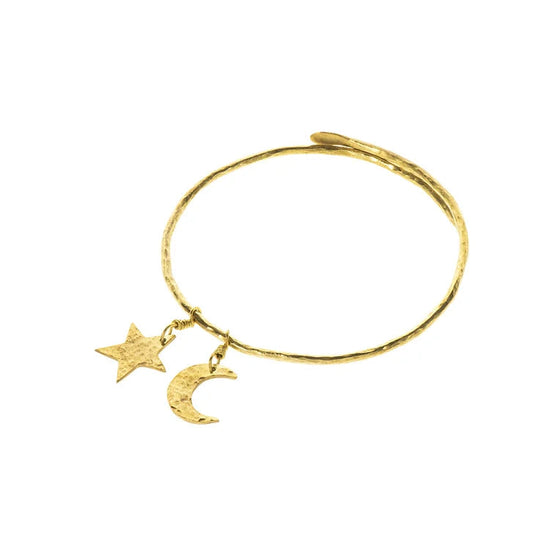 A single boop brass bangle with two small pendants in the shape of a star and a new moon. White backdrop.