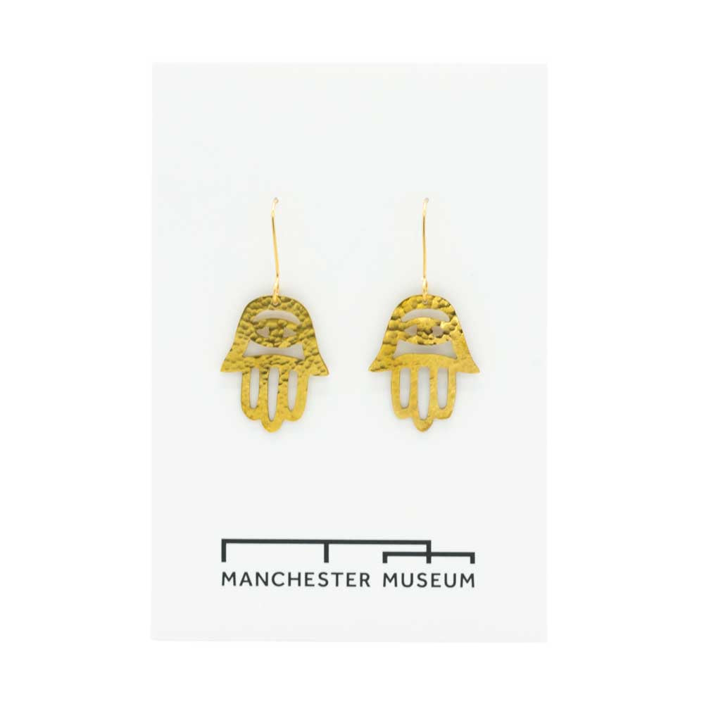 Brass earrings on the white museum branded card that is part of the sustainable packaging.
